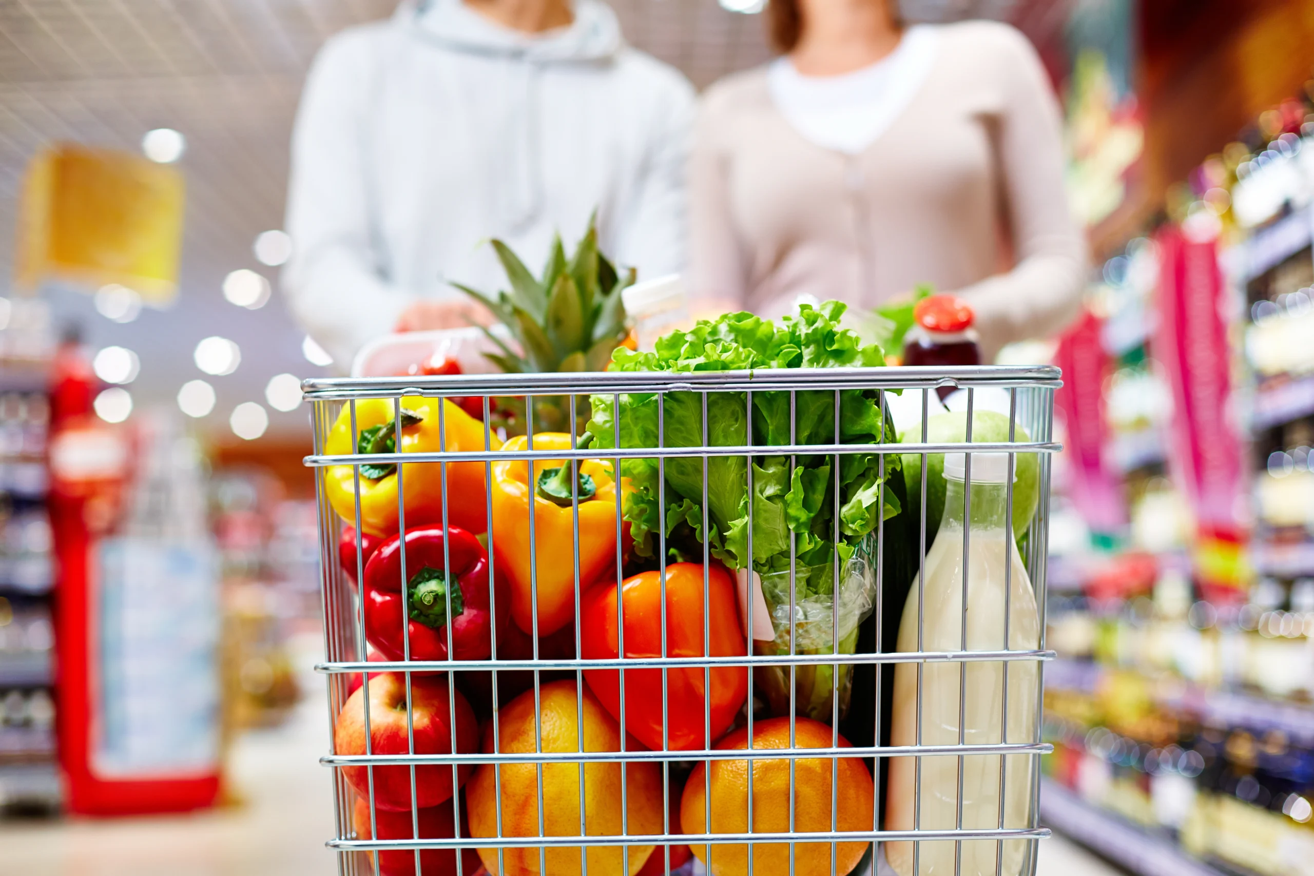 a man and a women doing grocery in the super store while holding the trolley
